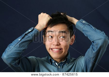 Funny young Asian man making face and looking sideways