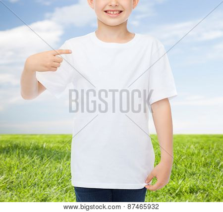advertising, people, childhood and t-shirt design concept - smiling little boy in white blank t-shirt pointing finger at himself over blue burst rays background