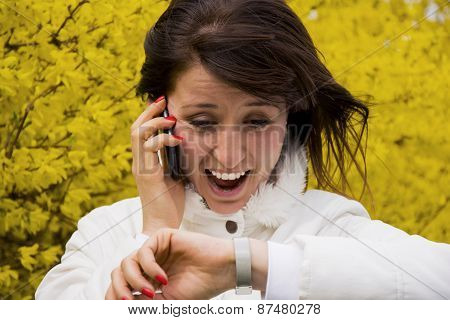 Young Woman Talking On The Phone And Looking At Wristwatch
