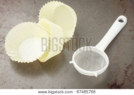 three yellow baking cups and sifter