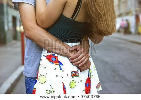 Guy hugs girl, focus on from behind his back in her arms