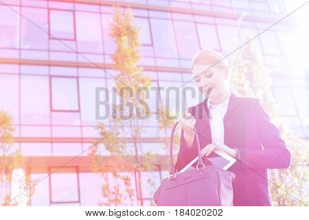 Businesswoman putting digital tablet in purse on sunny day