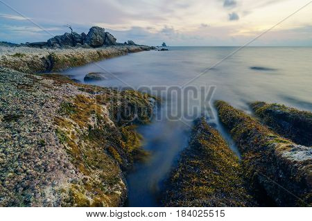 Long exposure of sea & rocks during beautiful evening at Labuan island,Malaysia.Known as Bonsai lonely tree Layang Layangan & lconic landmark in Labuan island,Malaysia.
