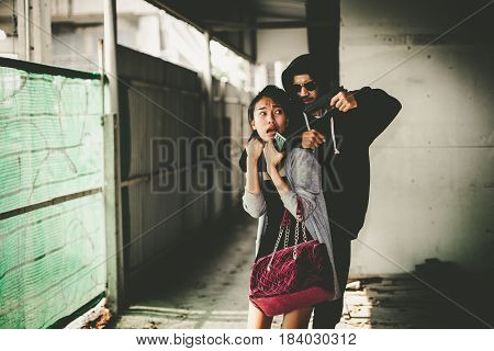 Man In Hoodie Robbing And Threatening With Gun To Frightened Young Woman. Criminal And Robbery For W