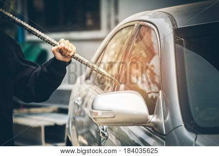 A Robber Dressed In Black Holding Crowbar At A Driver In A Car. Car Thief Concept.