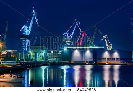 Giant cranes at shipyard at night covered in light