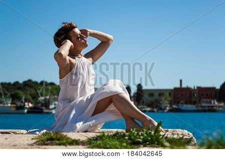 Female sunbathing on pier with blue sky in the background