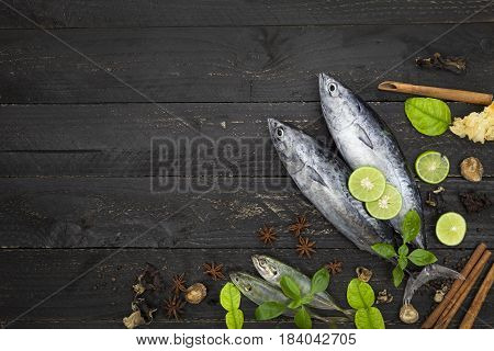 Fresh fish on dark black background Fish with spices and vegetables cooking background concept