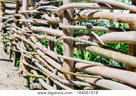 A woven wooden fence made of thin old branches in the countryside