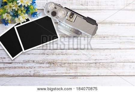 Vintage film camera and two blank photo frames on wooden table. Top view with copy space for design