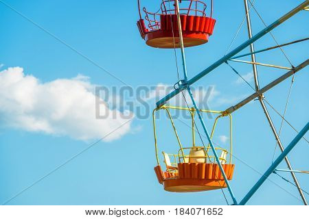 Colorful cabins of Ferris wheel on a background of blue sky with cloud