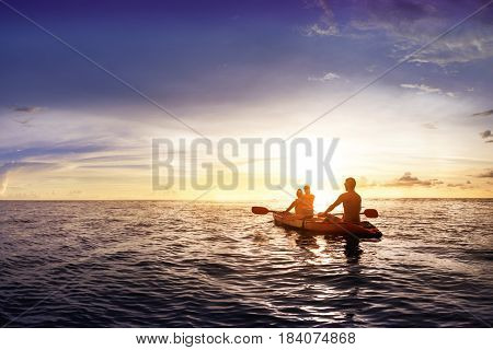Travel concept with family swimming in sea on kyak at sunset backdrop. Space for text