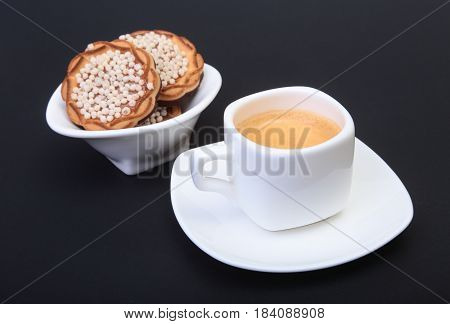 Classic espresso in white cup with homemade cake on black background. Selective focus