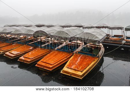 Many boats waiting for tourists on a misty lake