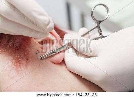 Professional holding the jewel of piercing just before screw the ball. Tragus type
