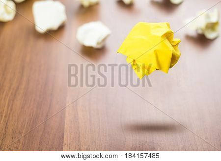 Yellow Crumpled Paper Ball Floating Around White Paper Ball On Wood Table, Business Concept