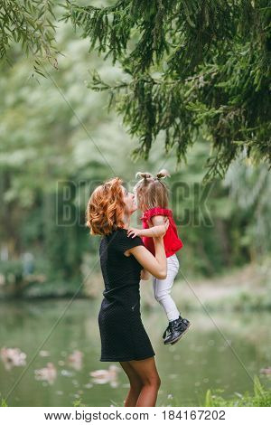 mom and little daughter walking in green summer park