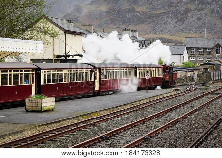 Blaenau Ffestiniog Wales UK - April 27 2017: A narrow gauge steam locomotive pulls out the station on track which first opened in 1836 the Ffestiniog Railway Company is the oldest surviving rail company in the world