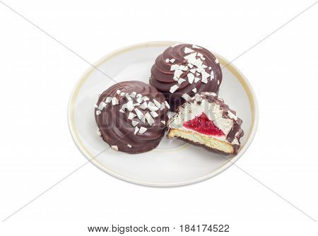 One half and two whole cookies with whipped egg whites and fruit jelly glazed with dark chocolate and sprinkled with chunks of white chocolate on the saucer on a light background