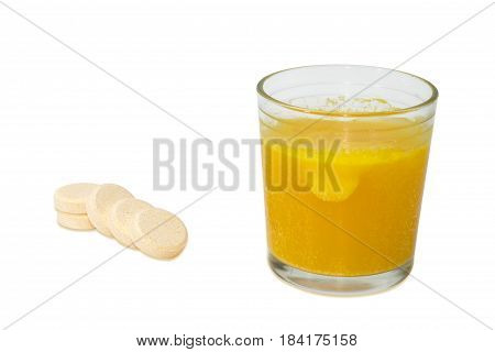 Effervescent medicinal tablet thrown into the glass of water and several same tablets separately beside closeup on a light background