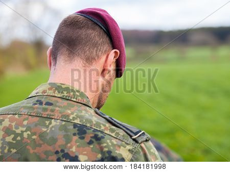 german soldier with a beret stands on a field background