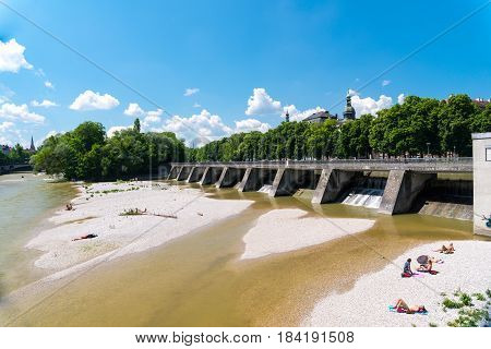Munich, Germany - June 7, 2016: People enjoy sunny hot weather on the river banks of Isar river in bavarian city Munich. The river becomes a giant beach during hot days.