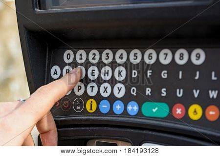Close up of male hand pressing buttons on parking meter with colorful buttons in the street