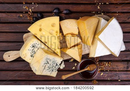 Various types of cheese on wooden table background. Cheddar, parmesan, emmental, blu cheese. Top view, copy space.