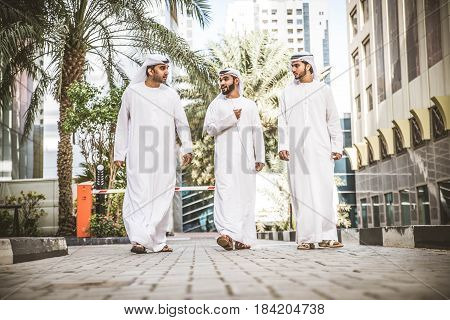 Three arabic men bonding outdoors - Businesspeople walking and talking in Dubai