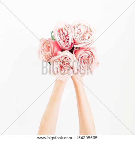 Bouquet of pink roses in feminini hands on white background. Flat lay, top view.