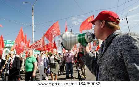 Orel Russia - May 1 2017: May demonstration. Man with loudspeaker talking to crowd with red Communist flags background