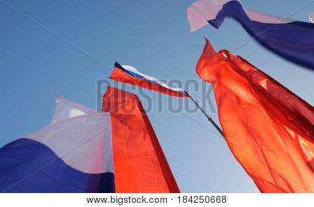 Orel Russia - May 1 2017: May demonstration. Russian tricolor and red Communist flags against clear blue sky