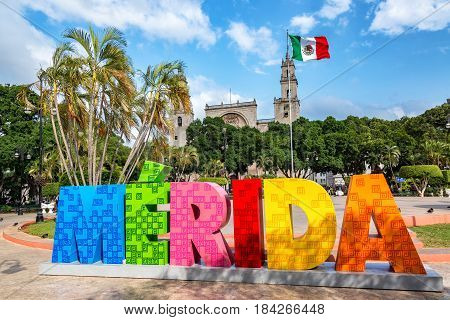 MERIDA MEXICO - FEBRUARY 21: Colorful Merida sign with a Mexican flag and cathedral in the background in Merida Mexico on February 21 2017