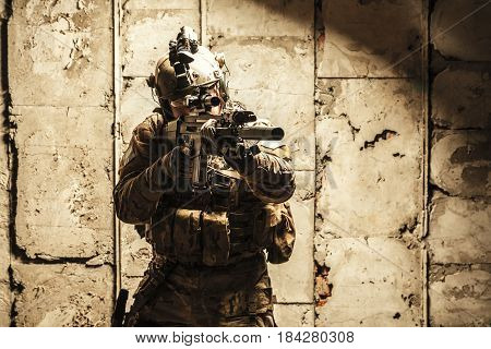 Army Ranger moving along the concrete wall on mission