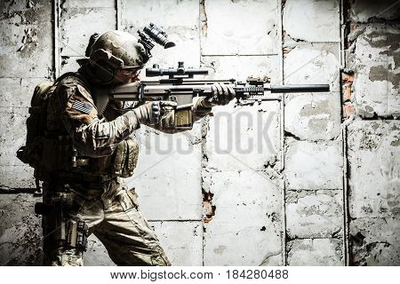 Army Ranger moving along the concrete wall on mission