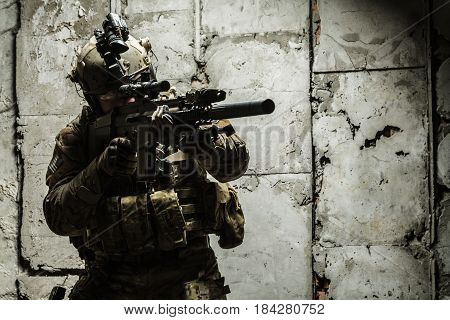 Army Ranger moving along the concrete wall on mission