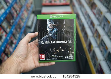 Bratislava, Slovakia, circa april 2017: Man holding Mortal Kombat XL  videogame on Microsoft XBOX One console in store