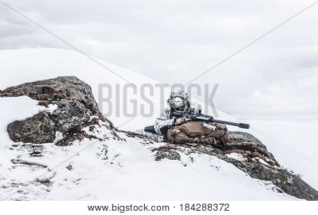 Army soldier with Sniper rifle in action in the Arctic. He lies among the cold rocks and stones, almost freezing to death, but waiting as long as enemies appear to kill them. Duty, service and loyalty