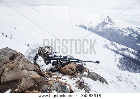 Army soldier with Sniper rifle in action in the Arctic. He lies among the cold rocks and stones, almost freezing to death, but waiting as long as enemies appear to kill them. Duty, service and loyalty
