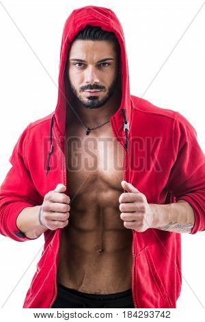 Muscular bodybuilder undressing, opening red hoodie sweater on naked muscle torso on light background
