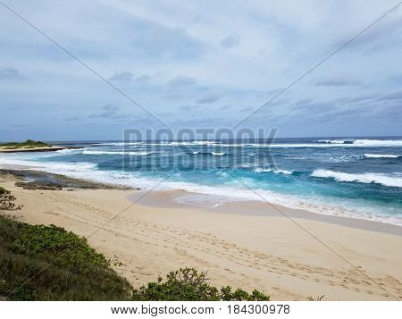 Waves break and crash towards the Hanakailio Beach with cloudy skyline on the North Shore of Oahu Hawaii.