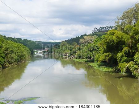 Panoramica of tranquil river current and banks with forests in day of clouds