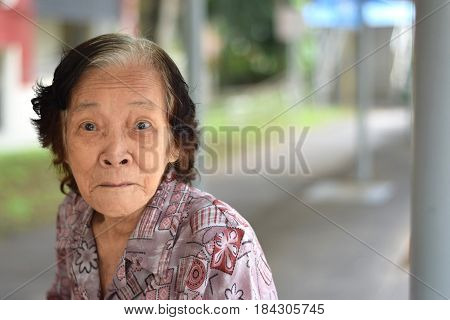 An elderly asian woman doing a funny look