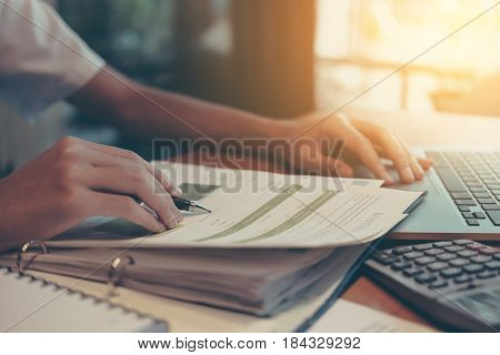 financeaccountingBusinessman analyzing investment charts with calculator laptop calculate technology in officebusiness conceptselective focusvintage color