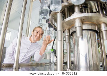 Female worker near conveyour at a water factory