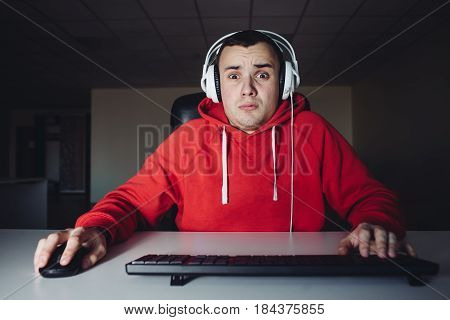 The young man plays a home game on his computer. Gamer fear looking at your computer monitor.