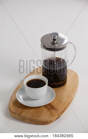 Cafetiere and a cup of black coffee on wooden tray