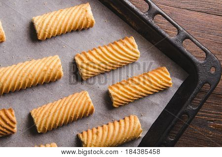 Homemade sweet cookies on a baking sheet. Baking in oven. On wooden background.