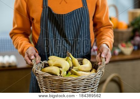 Mid section of vendor holding a basket of bananas