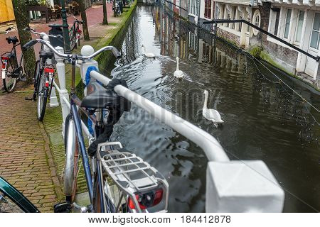 Canal with tunnel and historic street with bicycle parking lot in Dutch Delft old city